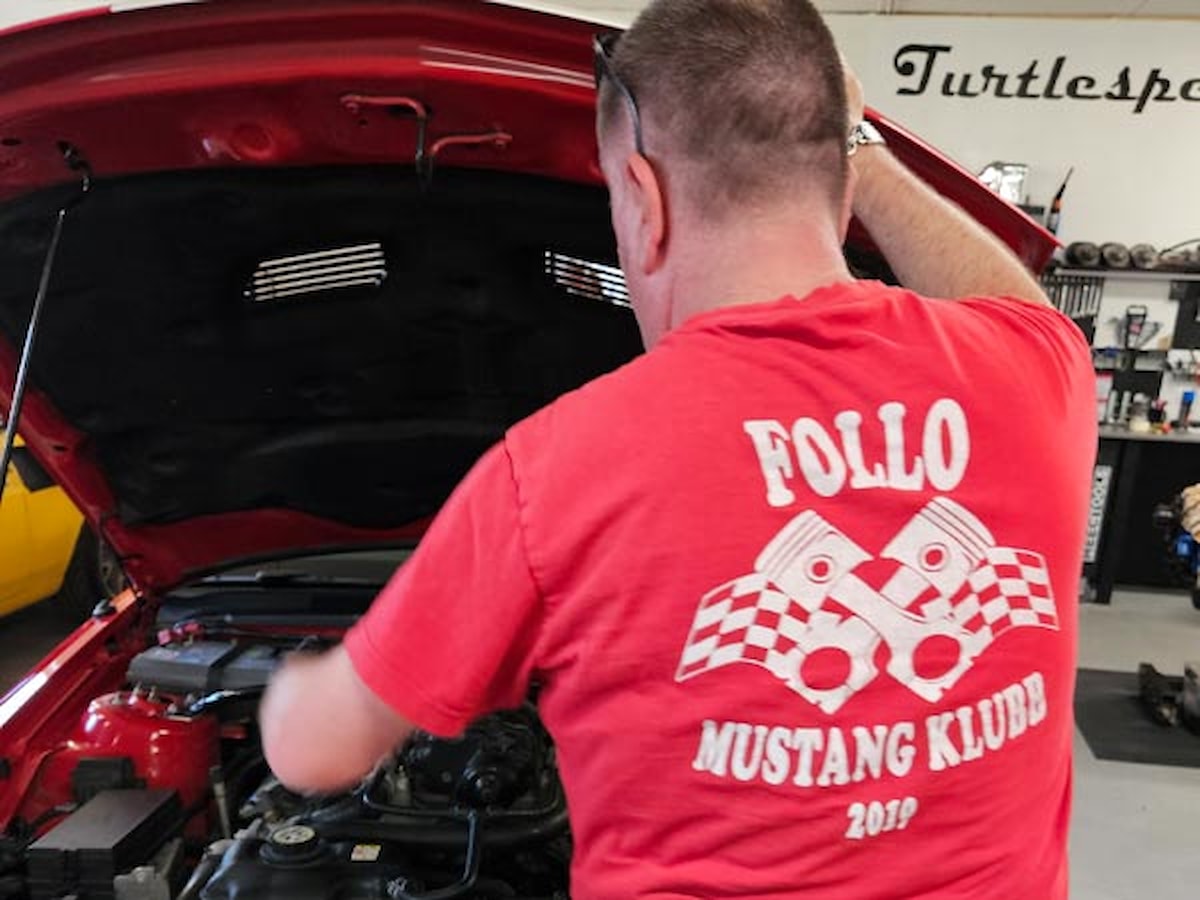 Medlem i Follo Mustangklubb som åpner panseret på bilen sin